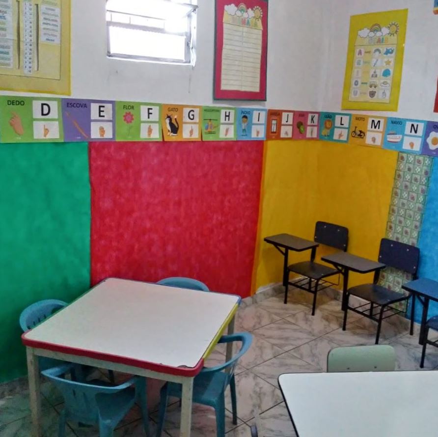 Sala de aula colorida com carteiras e alfabeto ilustrado